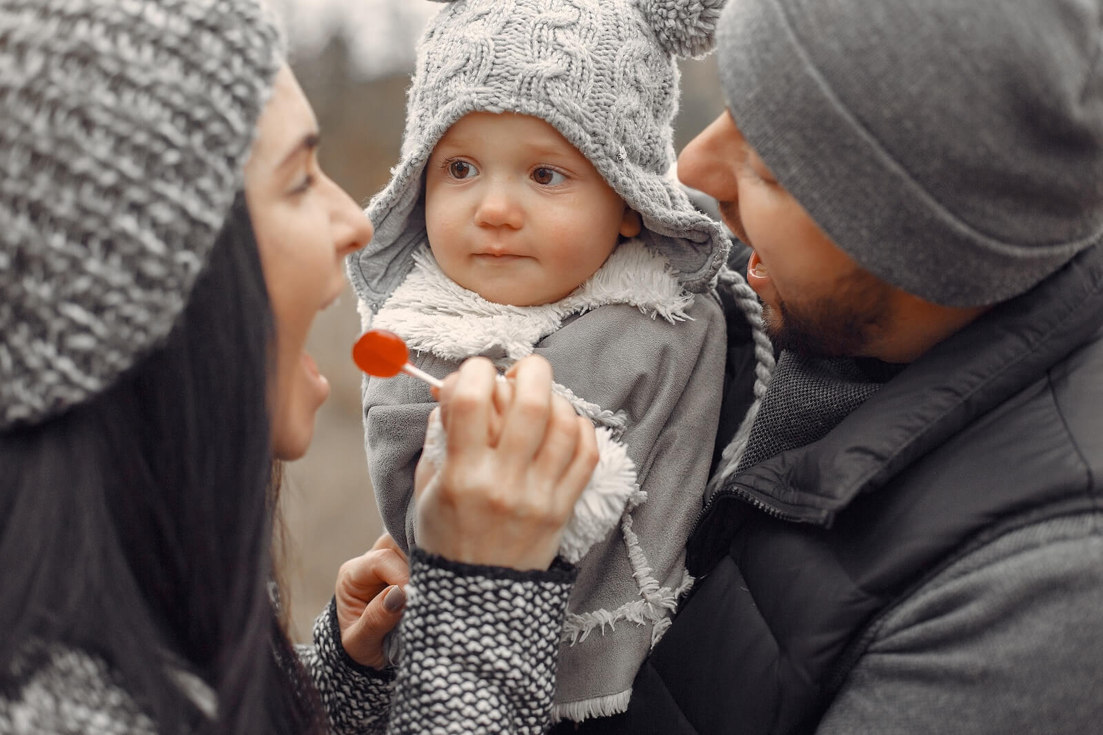 Mama und Papa machen Quatsch mit ihrem kleinen Kind auf dem Arm. Sie bitten um den Segen und eine Willkommensfeier als Alternative zur Taufe.